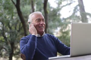 Person sitzt vor Laptop und telefoniert
