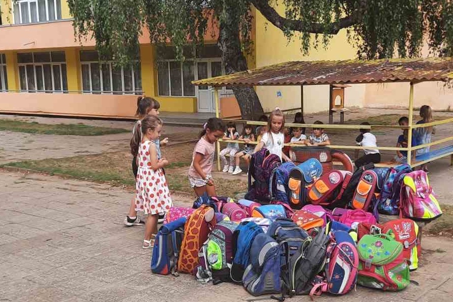 Die Schulranzen liegen auf einem Haufen und die Kinder sehen sie sich an.